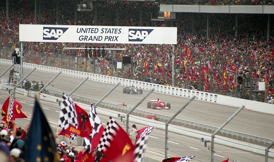 Michael Schumacher crossing the finish line at the 2000 United States Grand Prix in Indianapolis, with Tony George waving the chequered flag